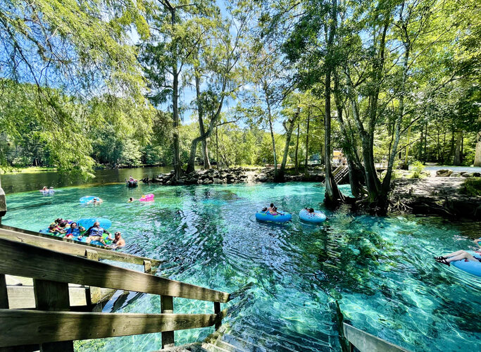 Tubers and swimmers float in the shallow clear aqua spring waters near Devil's Eye in the Devil's Run spring, Ginnie Springs, Florida